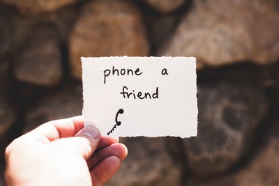 一个人拿着一张纸和朋友打电话写短信